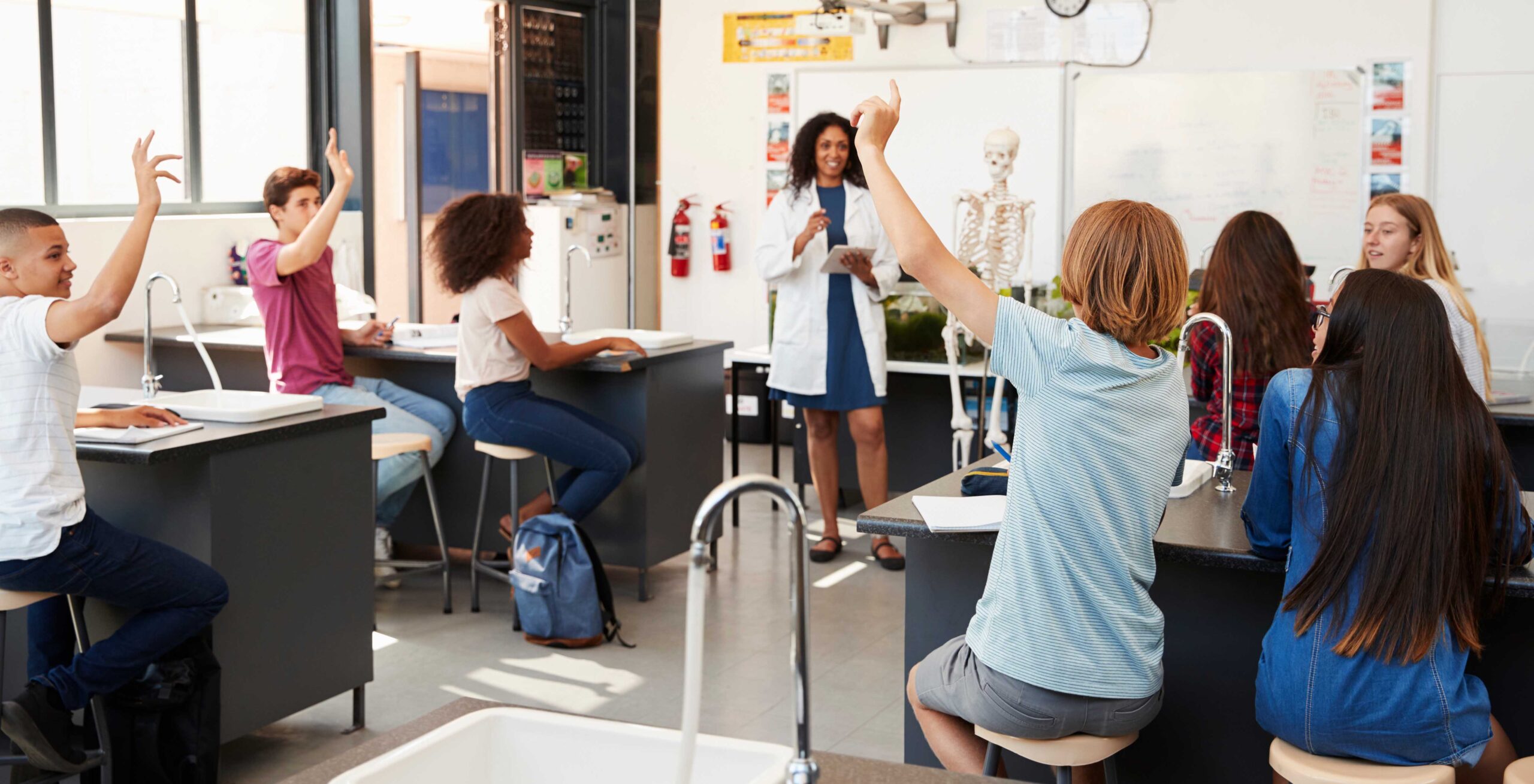 Pupils raising hands in a high school science lesson