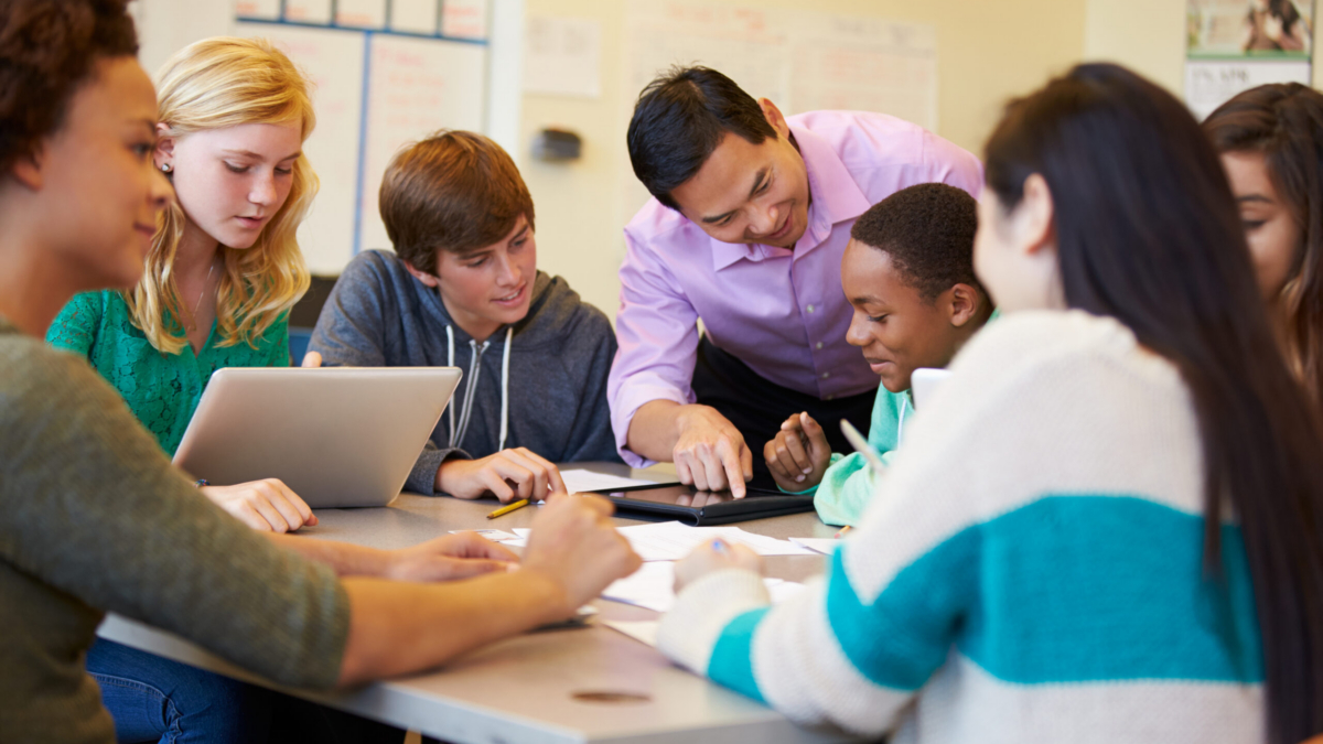 High School Students With Teacher In Class Using Laptops